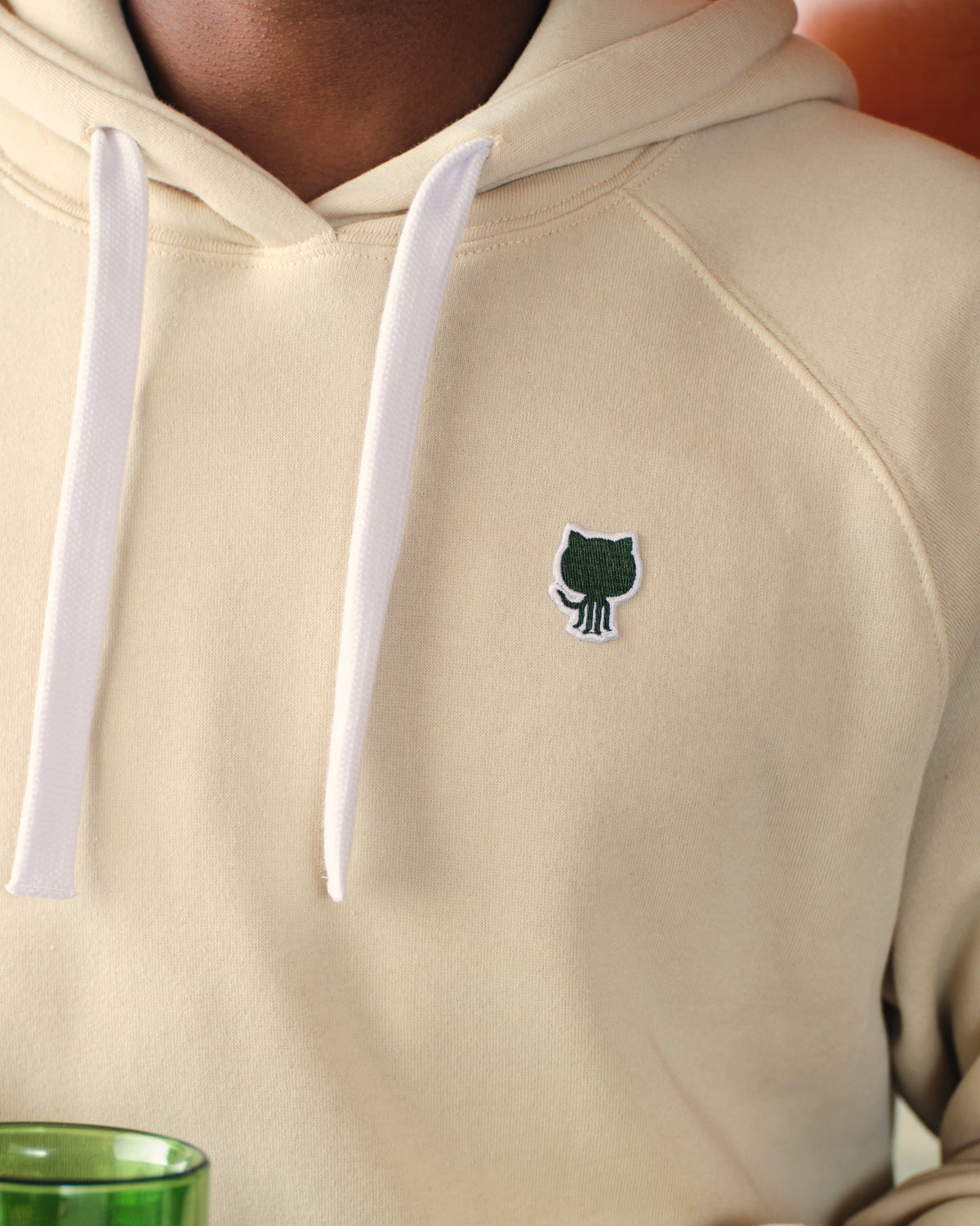 Detail view of Sportiqe Logo Patch Hoodie showing the green embroidered Octocat logo