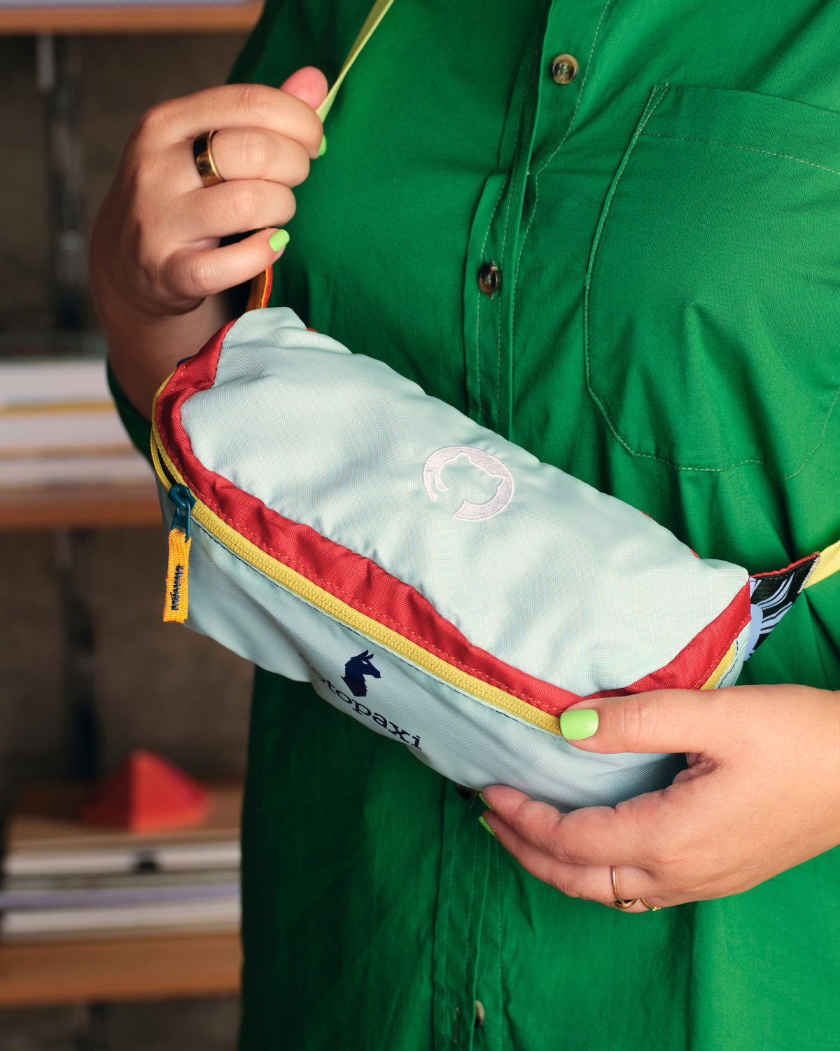 woman in green shirt holding Cotopaxi Bataan Hip Pack