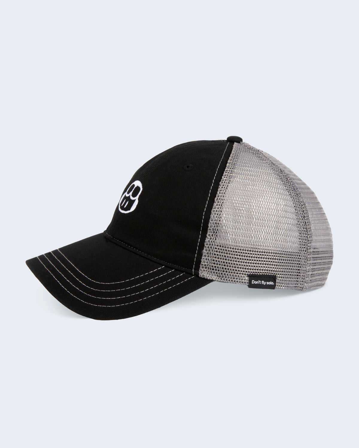 Side view of trucker hat in black with gray mesh on the back and black GitHub label attached on the side