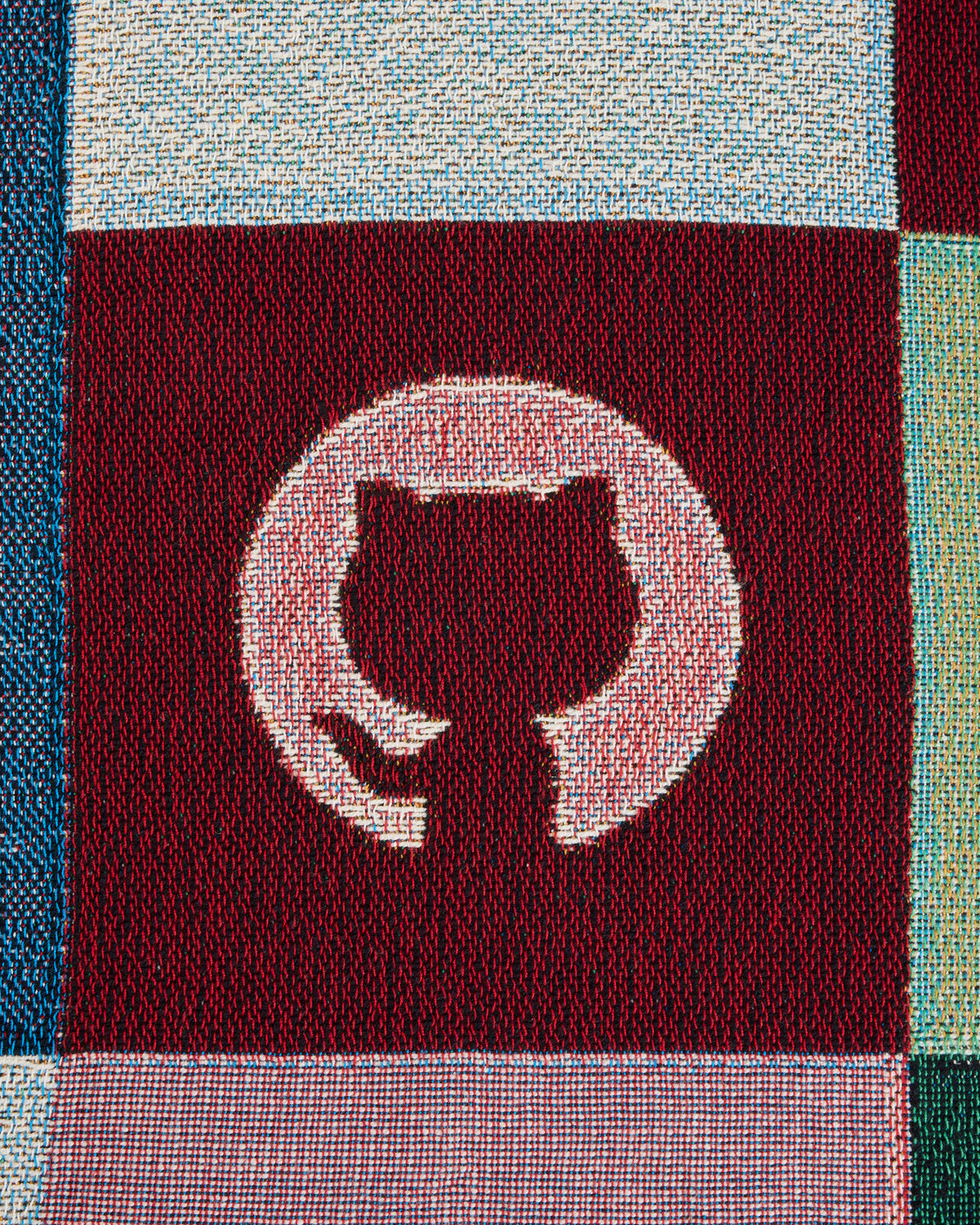 Close up look of woven blanket with GitHub logo.