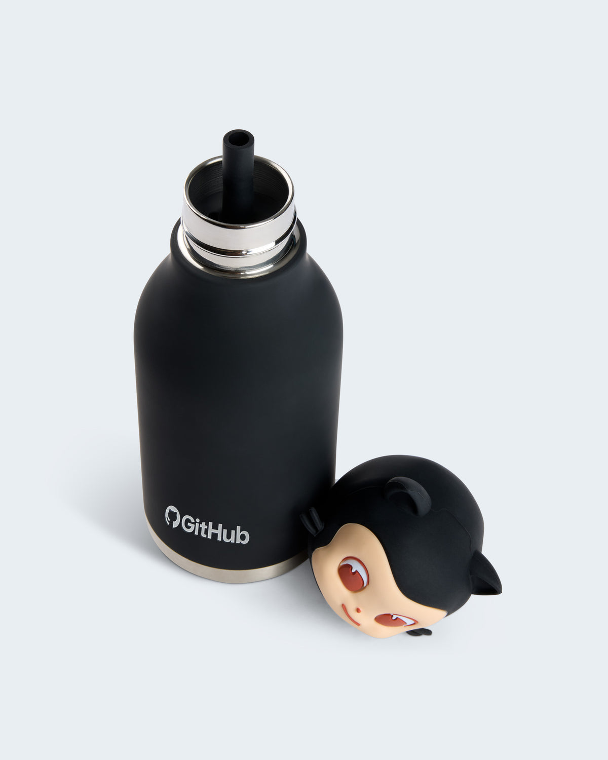 A matte black insulated bottle with a silver rim and a black straw, shown next to its matching black character cap featuring a Mona's face. The bottle has the GitHub logo printed on it.