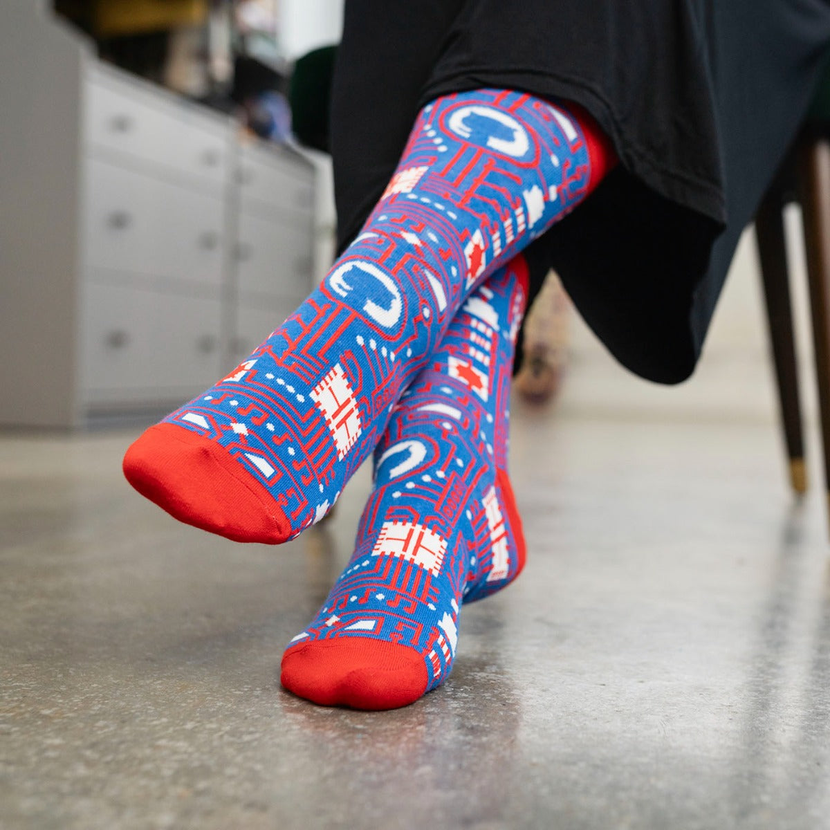 Lifestyle image of man wearing GitHub pattern dress socks in red.