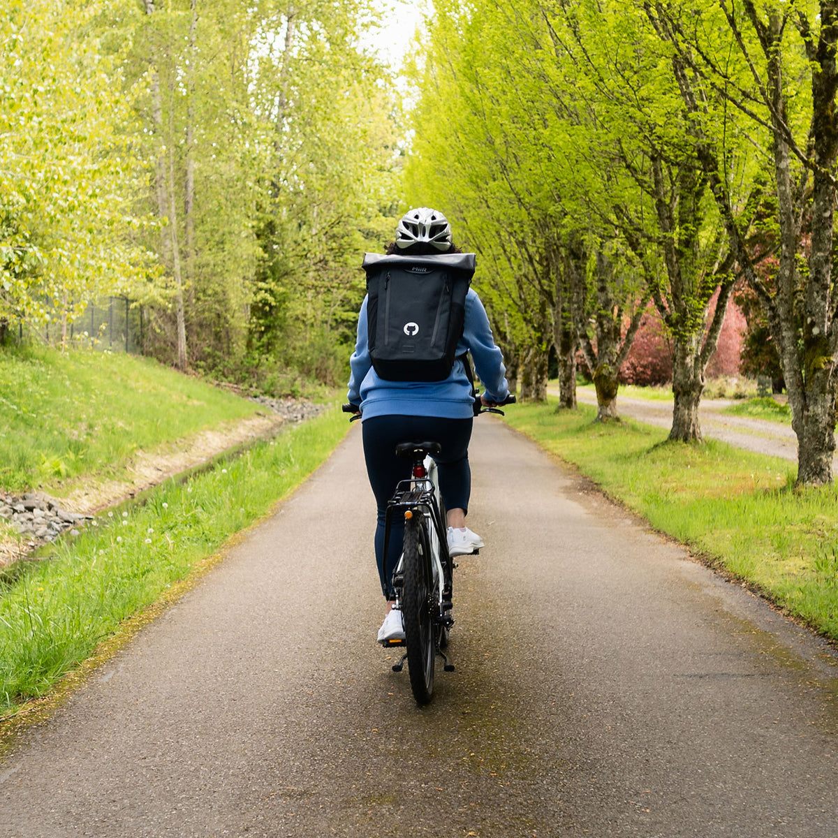 Photo of woman riding bicycle with Miir Laptop Backpack on her back.