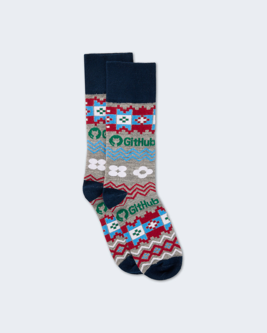 Pair of patterned crew socks featuring the GitHub logo and geometric designs in blue, red, gray, and white with dark navy cuffs, heels, and toes.