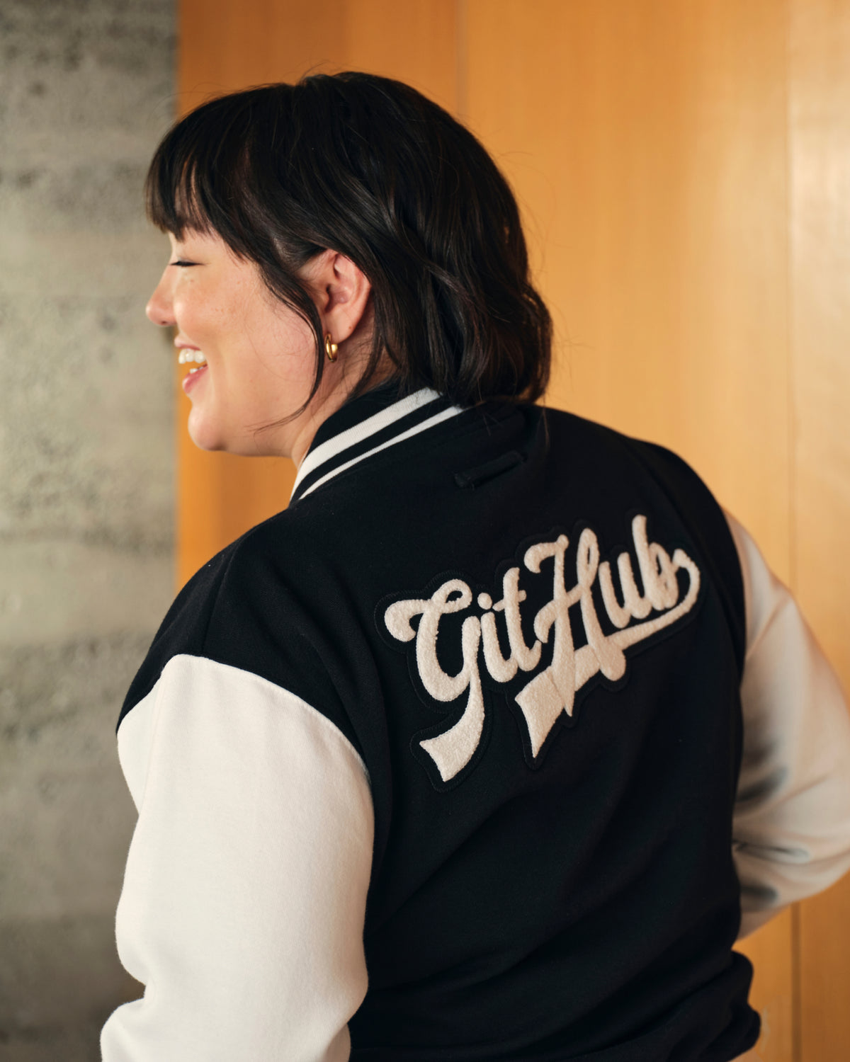 Photo of woman with black hair, smiling wearing Mona Varisty Jacket.