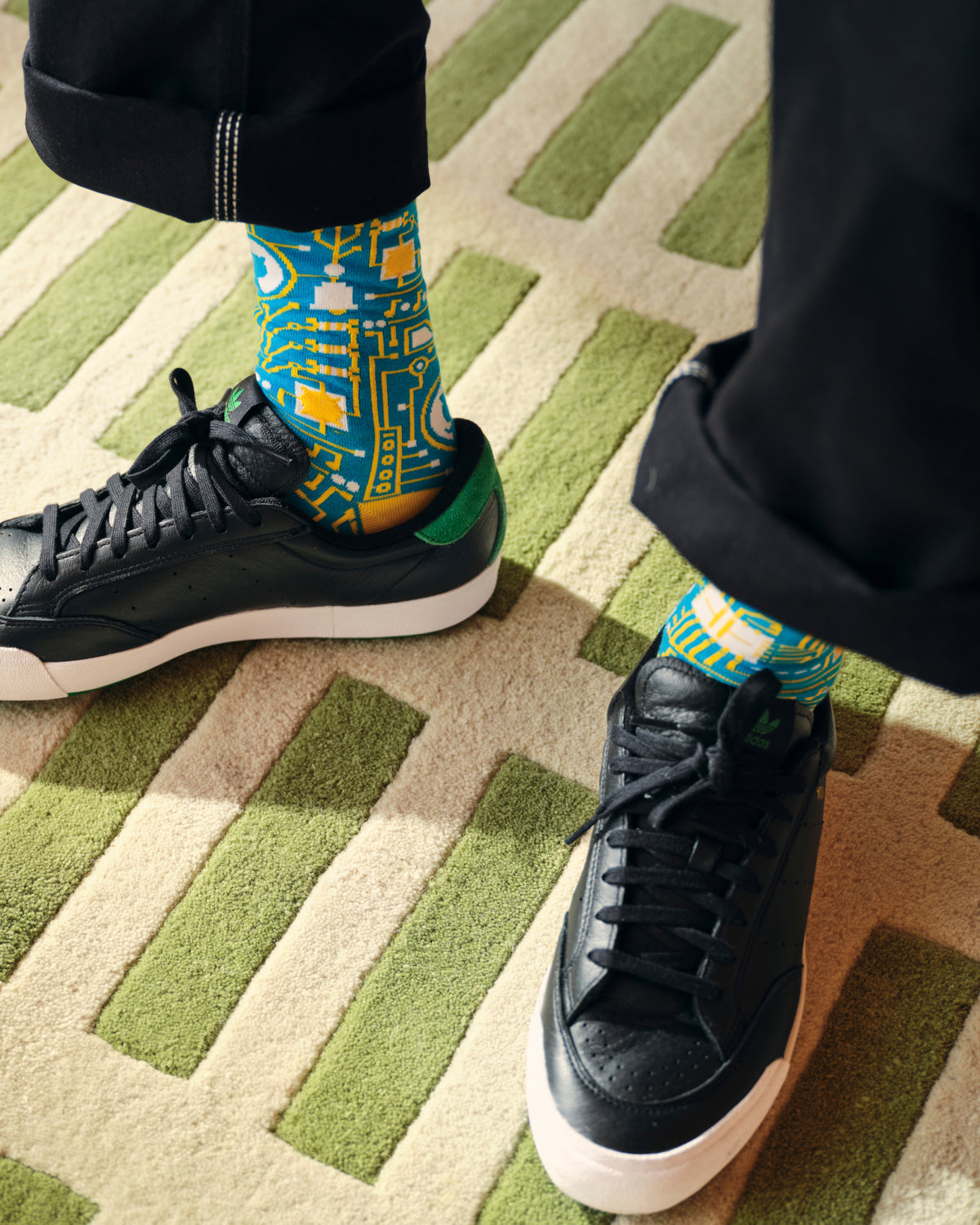 Lifestyle image of man wearing GitHub pattern dress socks in yellow.