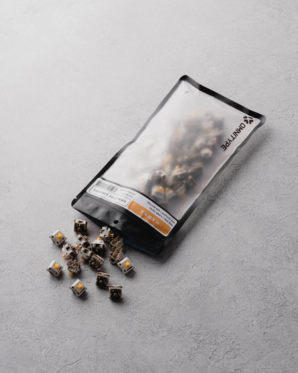 Mechanical keyboard switches partially spilled from a frosted storage pouch.